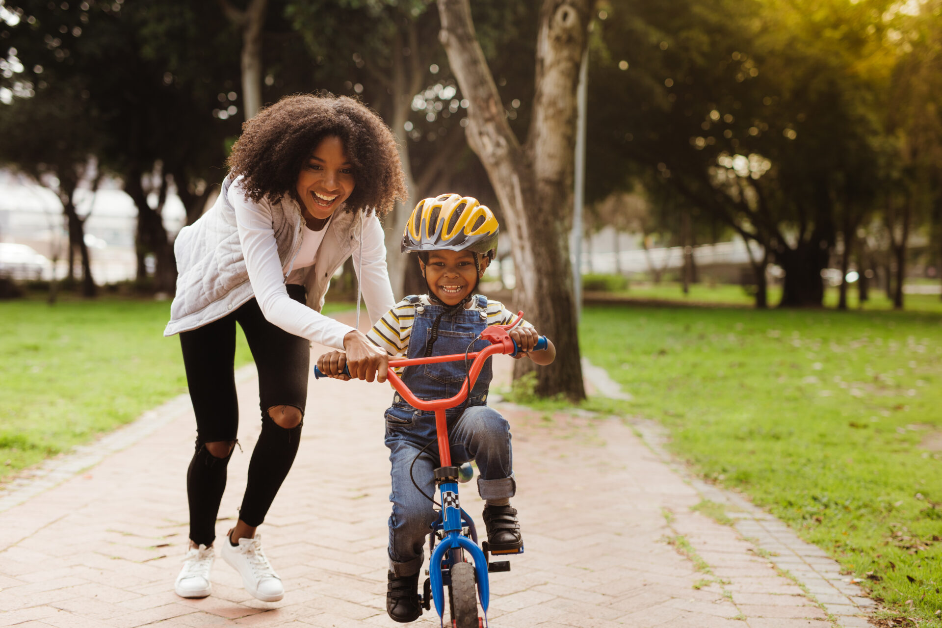 Mother teaching son how to ride a bike in the park.
